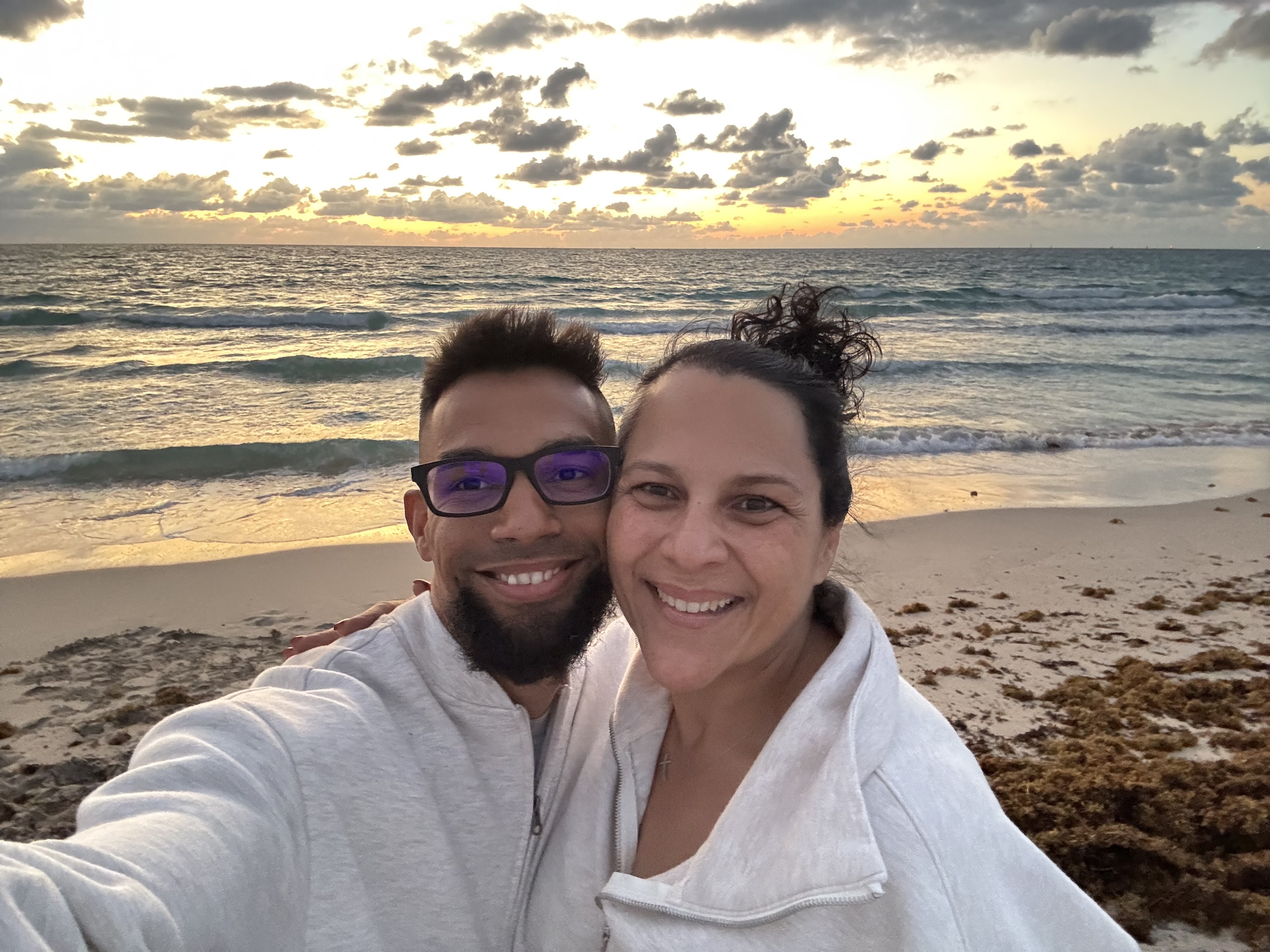 Omar and Yami Soto smiling together on the beach at sunset